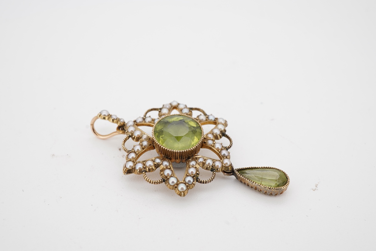 An Edwardian 15ct, peridot and seed pearl cluster pendant, set with circular and pear cut peridot, overall 39mm.